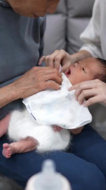 8 günlük Tayvanlı bir bebeğin dikey videosu mavi bir naylona sarılmış ve yeni doğan bir bebeğin fotoğrafını çekiyor.