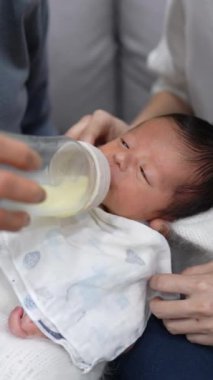 8 günlük Tayvanlı bir bebeğin dikey videosu mavi bir naylona sarılmış ve yeni doğan bir bebeğin fotoğrafını çekiyor.