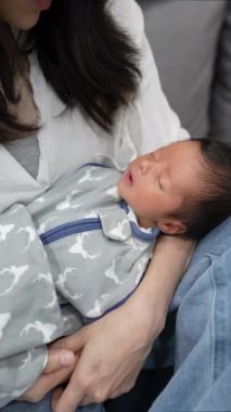 30 'larında Tayvanlı bir kadın 8 günlük bebeğini evdeki kanepede tutuyor..