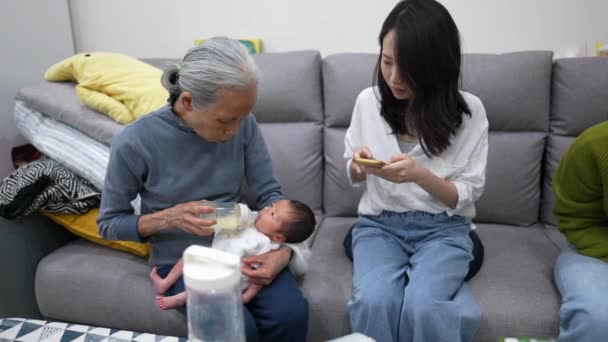 一位70多岁的台湾祖母和一位30多岁的母亲给一位身穿白色服装的8天大婴儿喂奶的慢镜头 — 图库视频影像