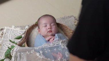 30 'lu yaşlarda Japon bir fotoğrafçı 32 günlük Tayvanlı bir bebeğin mavi bir ambalaja sarılı fotoğrafını çekiyor.