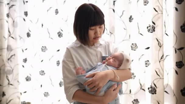 一位20多岁的台湾母亲在室内窗帘前扭伤了一位1个月大的女婴 — 图库视频影像