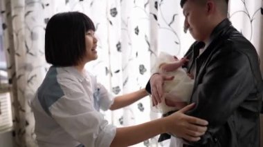 20 'li yaşlarında Tayvanlı bir anne ve baba perdenin önünde 1 aylık bir kızla dikiliyorlar..