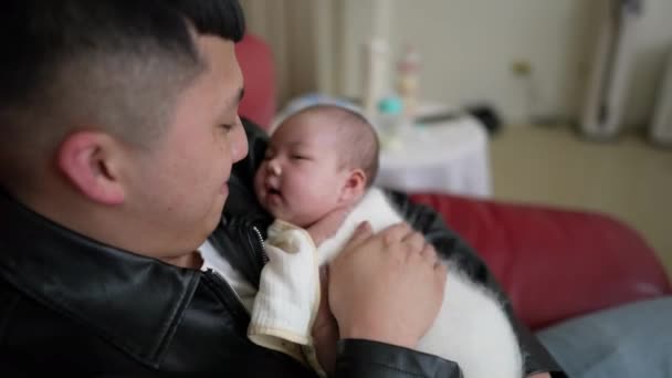 一位台湾人的父亲和一个多月大的女婴坐在一个红色的沙发上 — 图库视频影像