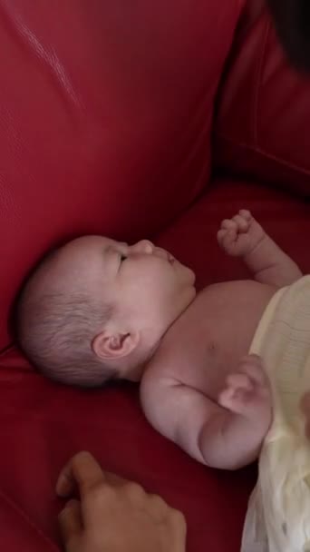 20代の台湾人の母親が赤いソファーで1ヶ月の女の子の赤ちゃんを変えた垂直ビデオ — ストック動画