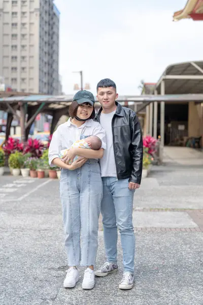 台湾宜兰一位20多岁的母亲和父亲抱着一个多月大的台湾婴儿 站在宜兰县罗东车站前 图库图片