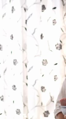 20 'li yaşlarda Tayvanlı bir annenin 1 aylık bir kızı iç mekan perdesinin önünde becerdiği dikey yavaş çekim videosu.