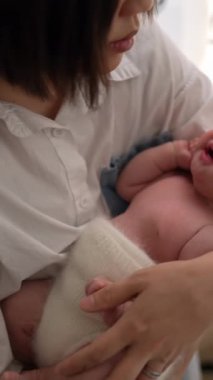 20 'li yaşlarda Tayvanlı bir annenin 1 aylık bir kızı iç mekan perdesinin önünde becerdiği dikey yavaş çekim videosu.