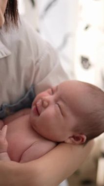 20 'li yaşlarda Tayvanlı bir annenin 1 aylık bir kızı iç mekan perdesinin önünde becerdiği dikey yavaş çekim videosu.