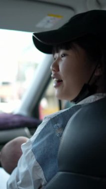 20 'li yaşlarda Tayvanlı bir anne ve babanın, 1 aylık bir bebeği arabada tutarken çekilmiş dikey ağır çekim videosu.