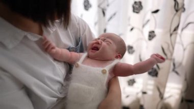 20 'li yaşlarda Tayvanlı bir annenin 1 aylık bir kızın bebeğini odanın perdesinin önünde şarkı söylerken ki yavaş çekim videosu.