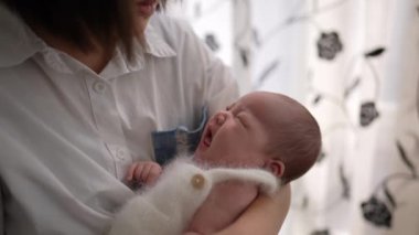 20 'li yaşlarda Tayvanlı bir annenin 1 aylık bir kızın bebeğini odanın perdesinin önünde şarkı söylerken ki yavaş çekim videosu.