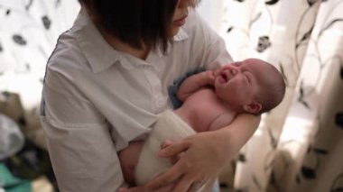 20 'li yaşlarda Tayvanlı bir annenin 1 aylık bir kızın bebeğini odanın perdesinin önünde şarkı söylerken ki yavaş çekim videosu.
