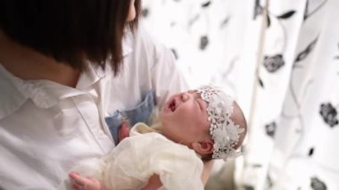 20 'li yaşlarda Tayvanlı bir annenin 1 aylık bir kızın bebeğini odanın perdesinin önünde şarkı söylerken ki yavaş çekim videosu.