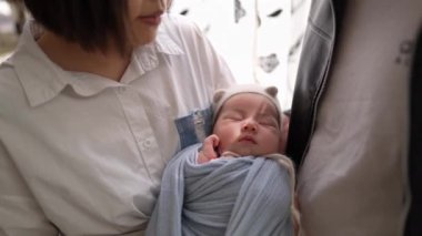 20 'li yaşlarında Tayvanlı bir anne ve babanın 1 aylık bir kızla perdenin önünde durduğu yavaş çekim videosu..