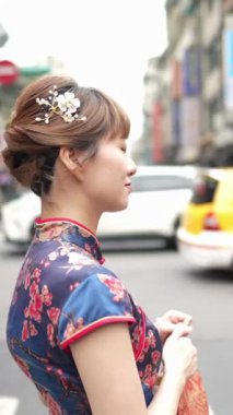 Tayvan, Tayvan 'da Wanhua bölgesinde geleneksel Çin elbisesi giyen 20' li yaşlarda bir Tayvanlı kadının yaya geçidinde akıllı bir telefonla yürüdüğü dikey yavaş çekim videosu.