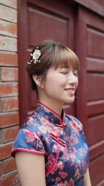 Tayvanlı bir kadının 20 'li yaşlarında, tarihi Bopiliao Tarihi Bloğu, Wanhua Bölgesi, Tayvan Şehri' nde yaya geçidinde dikilen geleneksel bir Çin elbisesi giymiş dikey yavaş çekim videosu.