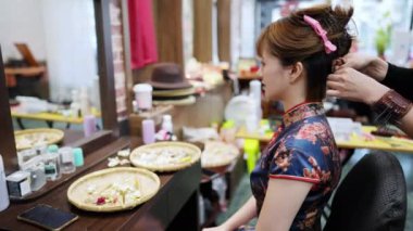Taipei 'nin Wanhua Bölgesi, Bopiliao' da tarihi bir sokakta canlı bir Cheongsam tarzı olan zarif genç bir Tayvanlı kadın geleneksel eşya ve mağazalarla çevrili bir şekilde oturuyor..