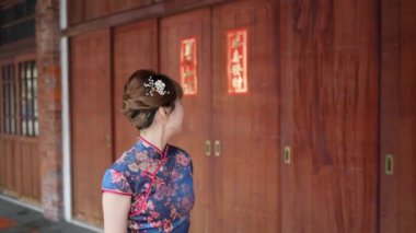 Tayvanlı genç bir kadın mavi çiçekli Cheongsam elbisesiyle Bopiliao Old Street, Wanhua District, Taipei City 'de kemerli sütunlarda yürüyor. Yavaş çekim
