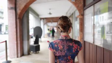 Tayvanlı genç bir kadın mavi çiçekli Cheongsam elbisesiyle Bopiliao Old Street, Wanhua District, Taipei City 'de kemerli sütunlarda yürüyor. Yavaş çekim