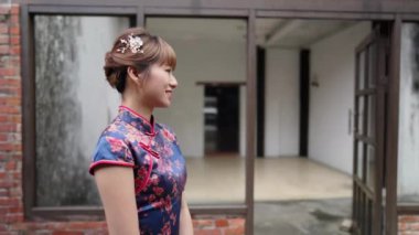 Tayvanlı genç bir kadın mavi çiçekli Cheongsam Tuğla duvarın yanında duruyor Wanhua Bölgesi, Taipei şehrindeki Bopiliao Old Caddesi boyunca.