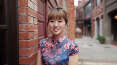 Tayvanlı genç bir kadın mavi çiçekli Cheongsam Tuğla duvarın yanında duruyor Wanhua Bölgesi, Taipei şehrindeki Bopiliao Old Caddesi boyunca.
