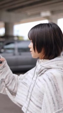  Causeway Körfezi 'nin göbeğinde, 20' li yaşlarda genç bir Hong Kong 'lu kadın akıllı telefonuyla filme alınıyor. Yavaş çekim etkisi, yoğun caddelerde dolaşırken yüzündeki huzurlu ifadeyi yakalıyor..