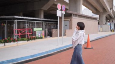 Genç bir kadın, Causeway Körfezi, Hong Kong 'un hareketli sokaklarında ağır çekimde şehir hayatının özünü yakalıyor. Rahatlamış tavrı, etrafındaki kentsel koşuşturmayla çelişiyor..
