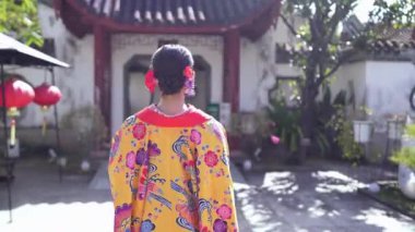 Geleneksel Ryusou giyimli yirmili yaşlarda genç bir kadın Okinawa 'daki güzel bir Çin bahçesinde zarifçe geziniyor. Çevrenin kültürel karışımını ve dingin güzelliğini vurguluyor..