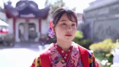 Geleneksel Ryusou giyimli yirmili yaşlarda genç bir kadın Okinawa 'daki güzel bir Çin bahçesinde zarifçe geziniyor. Çevrenin kültürel karışımını ve dingin güzelliğini vurguluyor..