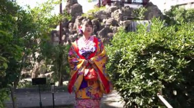 Geleneksel Ryusou giyimli yirmili yaşlarda genç bir kadın Okinawa 'daki güzel bir Çin bahçesinde zarifçe geziniyor. Çevrenin kültürel karışımını ve dingin güzelliğini vurguluyor..