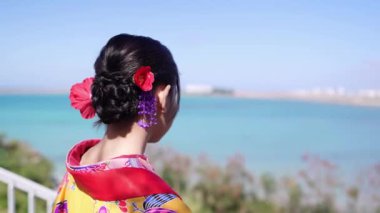 Geleneksel Ryusou giyimli yirmili yaşlarda genç bir kadın, Okinawa 'da güzel bir sahil kenarında duruyor. Okinawa' nın kültürel zarafetini ve doğal ihtişamını vurguluyor..