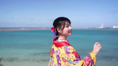 Geleneksel Ryusou giyimli yirmili yaşlarda genç bir kadın, Okinawa 'da güzel bir sahil kenarında duruyor. Okinawa' nın kültürel zarafetini ve doğal ihtişamını vurguluyor..