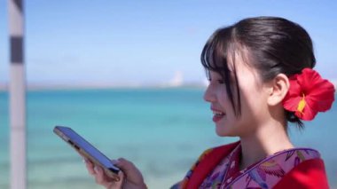 Geleneksel Ryusou giyimli yirmili yaşlarda genç bir kadın, Okinawa 'da güzel bir sahil kenarında duruyor. Okinawa' nın kültürel zarafetini ve doğal ihtişamını vurguluyor..