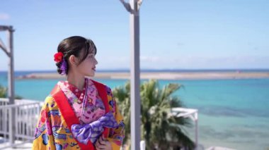 Geleneksel Ryusou giyimli yirmili yaşlarda genç bir kadın, Okinawa 'da güzel bir sahil kenarında duruyor. Okinawa' nın kültürel zarafetini ve doğal ihtişamını vurguluyor..