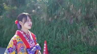 Geleneksel Ryusou giyen yirmili yaşlarında genç bir kadın Okinawa 'da açık havada yürüyor. Giysileri Okinawa geleneklerinin kültürel zarafetini ve tarihsel önemini vurguluyor..
