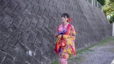 Geleneksel Ryusou giyen yirmili yaşlarında genç bir kadın Okinawa 'da açık havada yürüyor. Giysileri Okinawa geleneklerinin kültürel zarafetini ve tarihsel önemini vurguluyor..