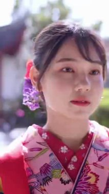 Geleneksel Ryusou giyen yirmili yaşlarında genç bir kadın Okinawa 'da Çin tarzı bir bahçede yürüyor. Bu sahne kültürel miras ve doğal güzelliğin karışımını vurgular..