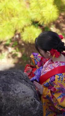 Geleneksel kıyafetler giyen yirmili yaşlarında genç bir kadın Okinawa 'da deniz kenarında merdivenlerden çıkar. Bu dikey yavaş çekim videosu onun zarif hareketini ve etrafındaki manzaralı güzelliği yakalıyor..