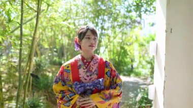 Yavaş çekimde, geleneksel Okinawa giysisine benzeyen bir kimono giymiş genç bir Japon kadın Çin tarzı bir bahçe içinde zarif bir bambu koruluğunun içinden geçerek huzurlu ve büyüleyici bir sahne yaratıyor..