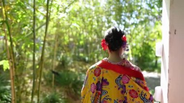 Yavaş çekimde, geleneksel Okinawa giysisine benzeyen bir kimono giymiş genç bir Japon kadın Çin tarzı bir bahçe içinde zarif bir bambu koruluğunun içinden geçerek huzurlu ve büyüleyici bir sahne yaratıyor..