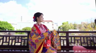 Geleneksel kıyafet giymiş 20 'li yaşlarda Japon bir kadın deniz kenarında akıllı telefonunu kullanıyor. Bu dikey yavaş çekim videosu, modern teknolojinin kültürel miras ile karışımını vurguluyor..