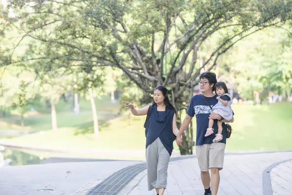 stock image Tender moments unfold as 30-something Chinese Malaysian parents play with their 1-year-old daughter in iconic KLCC Park. The family's joy contrasts beautifully with the urban oasis backdrop.