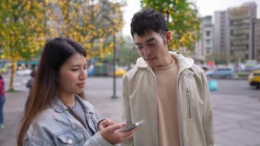 Tayvanlı genç bir çift 20 'li yaşlarda Taipei' nin Xinyi semtinin sokaklarında, akıllı telefon kullanan bir kadınla ve 20 'li yaşlarını gören bir adamla konuşuyor.