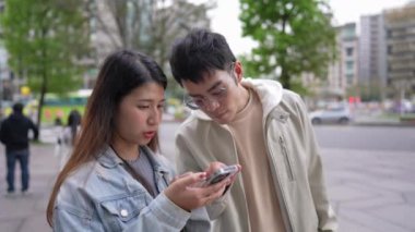 Tayvanlı genç bir çift 20 'li yaşlarda Taipei' nin Xinyi semtinin sokaklarında, akıllı telefon kullanan bir kadınla ve 20 'li yaşlarını gören bir adamla konuşuyor.
