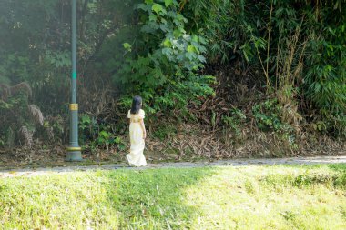 Bukit Jalil 'in pitoresk park havuzu, 25 küsur Çinli Malezyalı kadın için manzaralı bir zemin haline geliyor. Güneşli sarı elbisesi doğal manzaraya renk katıyor..