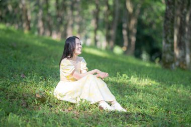 Bukit Jalik Parkı 'ndaki yemyeşil ormanda keman çalan Çinli genç bir kadının büyüleyici görüntüsü. Sarı elbisesi yeşil arkaplanda çarpıcı bir kontrastlık yaratıyor..