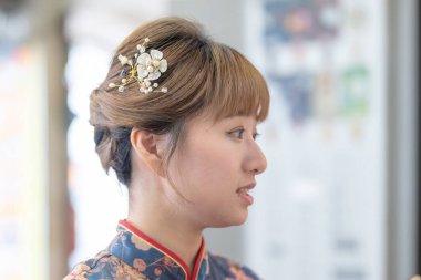 Canlı mavi Cheongsam 'lı şık bir Tayvanlı kadın Wanhua, Taipei' de hareketli bir sokakta köpüklü çay sipariş ediyor. Onun zarif kıyafeti modern içecekle çelişiyor, geleneğin bir karışımını sergiliyor.