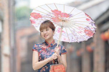 20 'li yaşlarda Tayvanlı genç bir kadın, mavi bir keongsam giyiyor. Elinde Çin desenli bir şemsiyeyle Wanhua, Taipei, Tayvan' da bir kültür bölgesinde geziniyor.