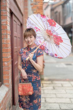 20 'li yaşlarda Tayvanlı genç bir kadın, mavi bir keongsam giyiyor. Elinde Çin desenli bir şemsiyeyle Wanhua, Taipei, Tayvan' da bir kültür bölgesinde geziniyor.